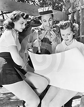 Two young women and a man looking at architectural plans