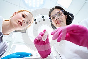 Two young women in medical uniforms are leaning over patient