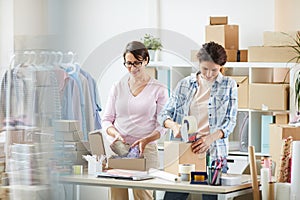 Two young women packing parcels for online clients