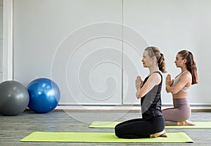 Two young women play yoga stretching, exercise for health in fitness, the concept of physical and mental health care