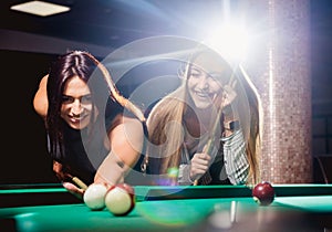 Two young women playing in billiard.