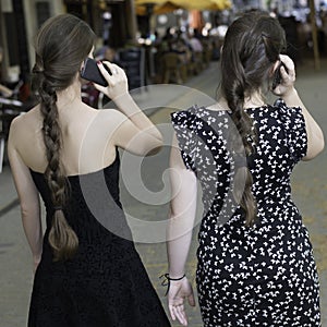 Two young women with ponytails talking on the phon