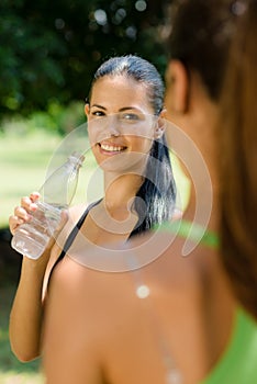 Two young women relaxing after fitness in park