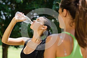 Two young women relaxing after fitness in park