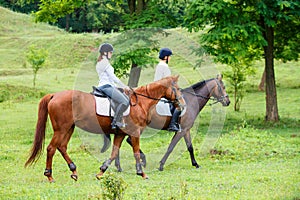 Two young women riding horse in park.