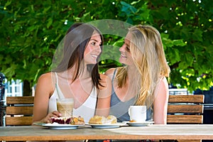 Two young women sitting close in outdoors cafe