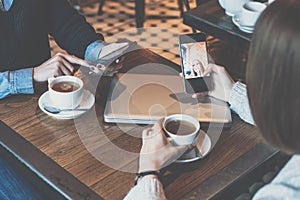 Two young women sitting at table in cafe and using smartphones.Girls shopping online.