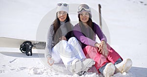 Two young women sitting waiting in the snow