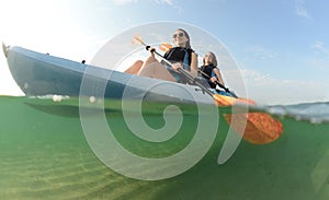 Two young women smiling in blue kayak