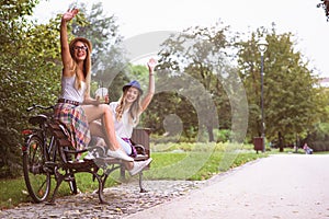 Two young women students in park sitting on park benchtalking