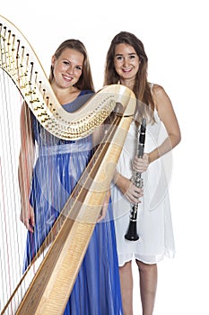 Two young women in studio with harp and clarinet against white b