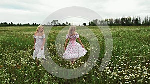 Two young women in summer dresses dancing in the field