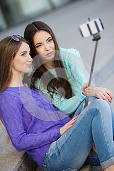 Two young women taking pictures with your smartphone.
