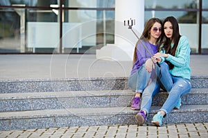 Two young women taking pictures with your smartphone.