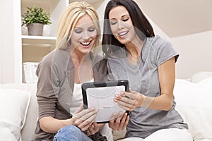 Two Young Women Using Tablet Computer At Home