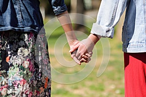 Two young women in walking holding her hands in urban park.