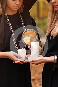 Two young women in Witch costume and hat looking mysteriously at candles