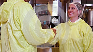 Two young worker man and woman handshake about agreement for success together in factory.