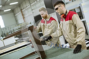 Two young workers assembling furniture in the factory