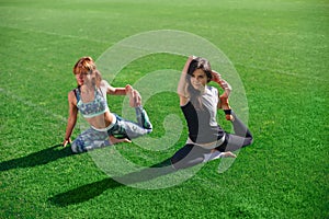 Two young yoga female doing yogatic exericise at the stadium.