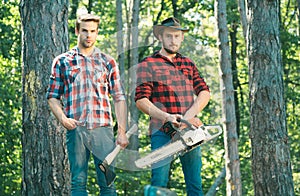 Two ypung Lumberjack man holds axe. Brutal lumberjack concept.