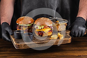 Two yummy big grilled burger with double meat cutlet and cheese on a wooden board ready to eat. Burger and fries.