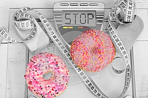 Two yummy pink donuts on a weight scale - weight loss