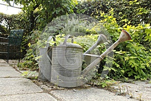 Two zinc watering cans in the garden in summer