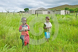 Two Zulu black boys in rural area of Zululand with village in background, South Africa