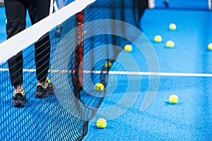 Twoo balls next to the net of a blue paddle tennis court. Sport healthy concept.