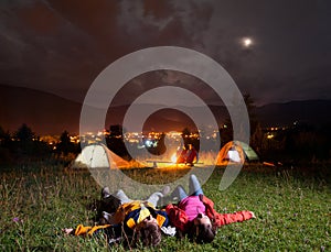 Twosome admiring the bright stars and lying on the grass