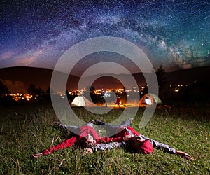 Twosome admiring the bright stars and lying on the grass