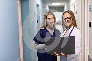 Twowoman healthcare workers using laptop in hospital