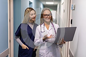 Twowoman healthcare workers using laptop in hospital