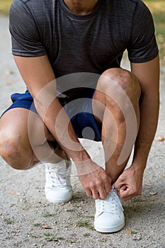 Tying lace shoelace shoes runner young man portrait format ready running jogging sports training fitness