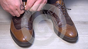 Tying the shoelaces of a pair of classic shoes. Side shot.