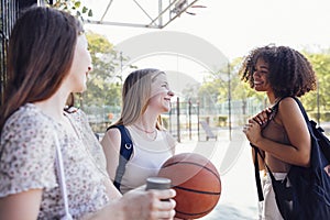 Tylish cool teen girls gathering at basketball court, friends ready for playing basketball outdoors