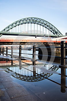 Tyne Bridge on Newcastle Quayside with reflection in puddle after rainstorm