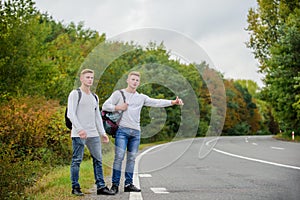 Type of adventure. On the road. Enjoying summer hike. Looking for transport. twins walking along road. stop car with