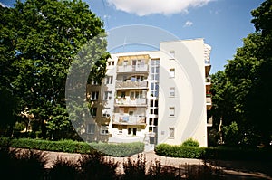 Types of houses concept. Outdoor analog photo of a white four-storey block of flats with white elevation. Beautiful