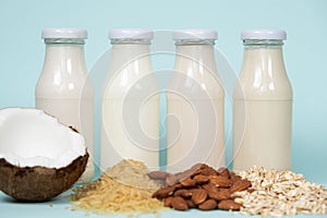 Types of plant-based milk in glass bottles. Coconut, rice, almond and oat milk on blue background. photo