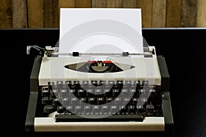 typewriter on the black table. White blank card. Wall of rough b