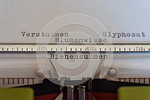 Typewriter with a leaf  and the words Verstummen, Glyphosat, Blumenwiese und Bienensummen Silencing, Glyphosate, Flower Meadow,