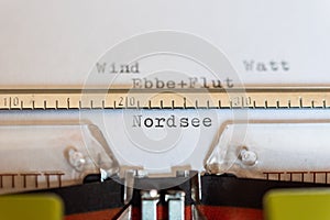 Typewriter with a leaf and the words Wind, Watt, Ebbe+Flut und NordseeWind, Watt, Ebb + tide and North Sea