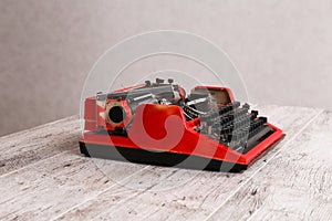 The typewriter is red with paper in it and on the table