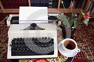 A typewriter, tea and a rose in a vase