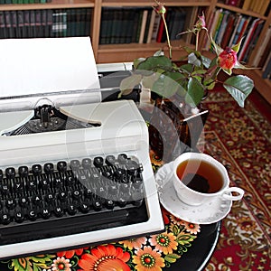 A typewriter, tea and a rose in a vase