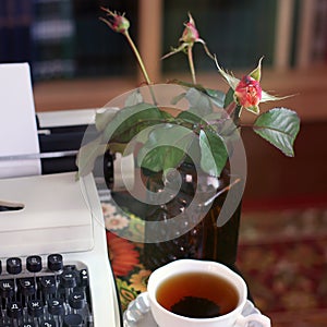 A typewriter, tea and a rose in a vase