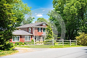 typical American two-story residential building with a well-maintained front yard and large trees in the yard