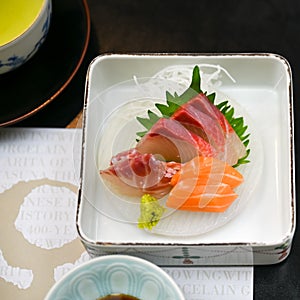 Typical appetizer in Japan with raw fish, tuna, salmon and yellowfin tuna with wasabi and lettuce leaf in Japanese porcelain